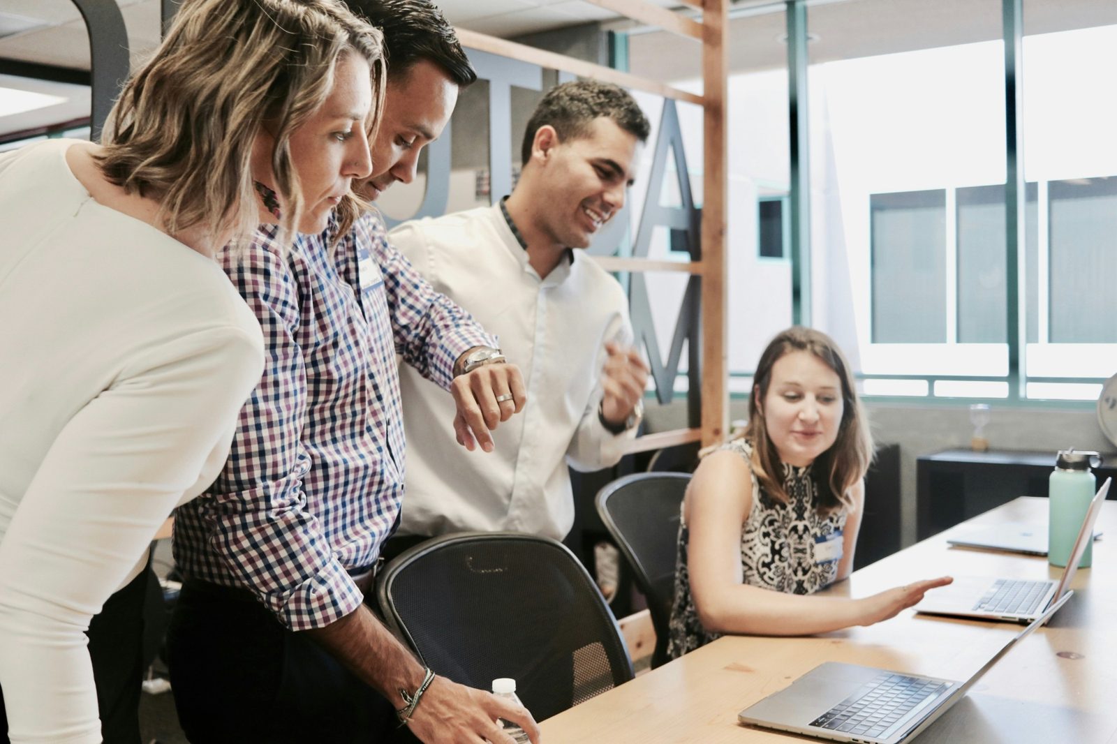 A team in a workshop gathered around a laptop, laughing